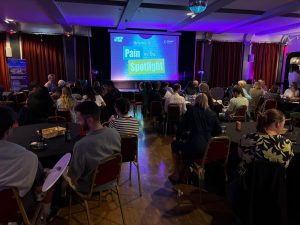 Attendees sat at tables, waiting for 'Pain in the Spotlight' to begin.